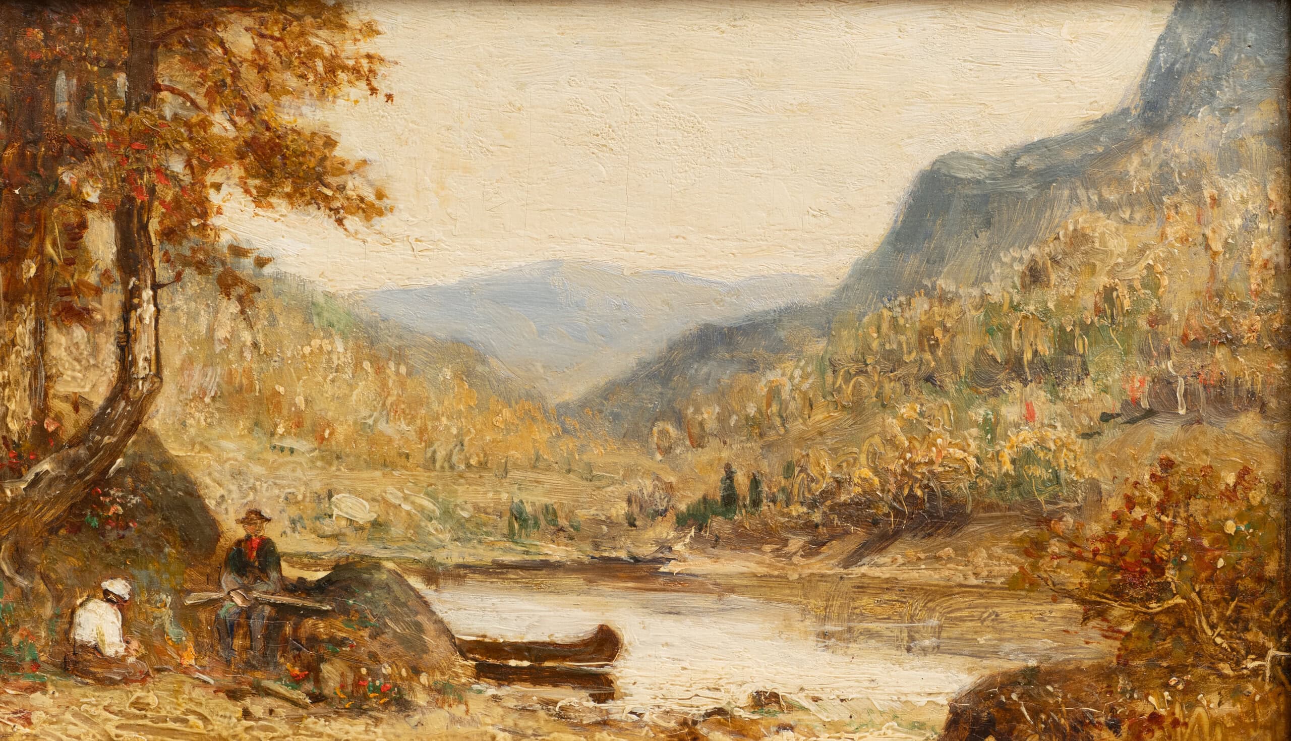 two men sitting lakeside next to canoe with mountains in the background