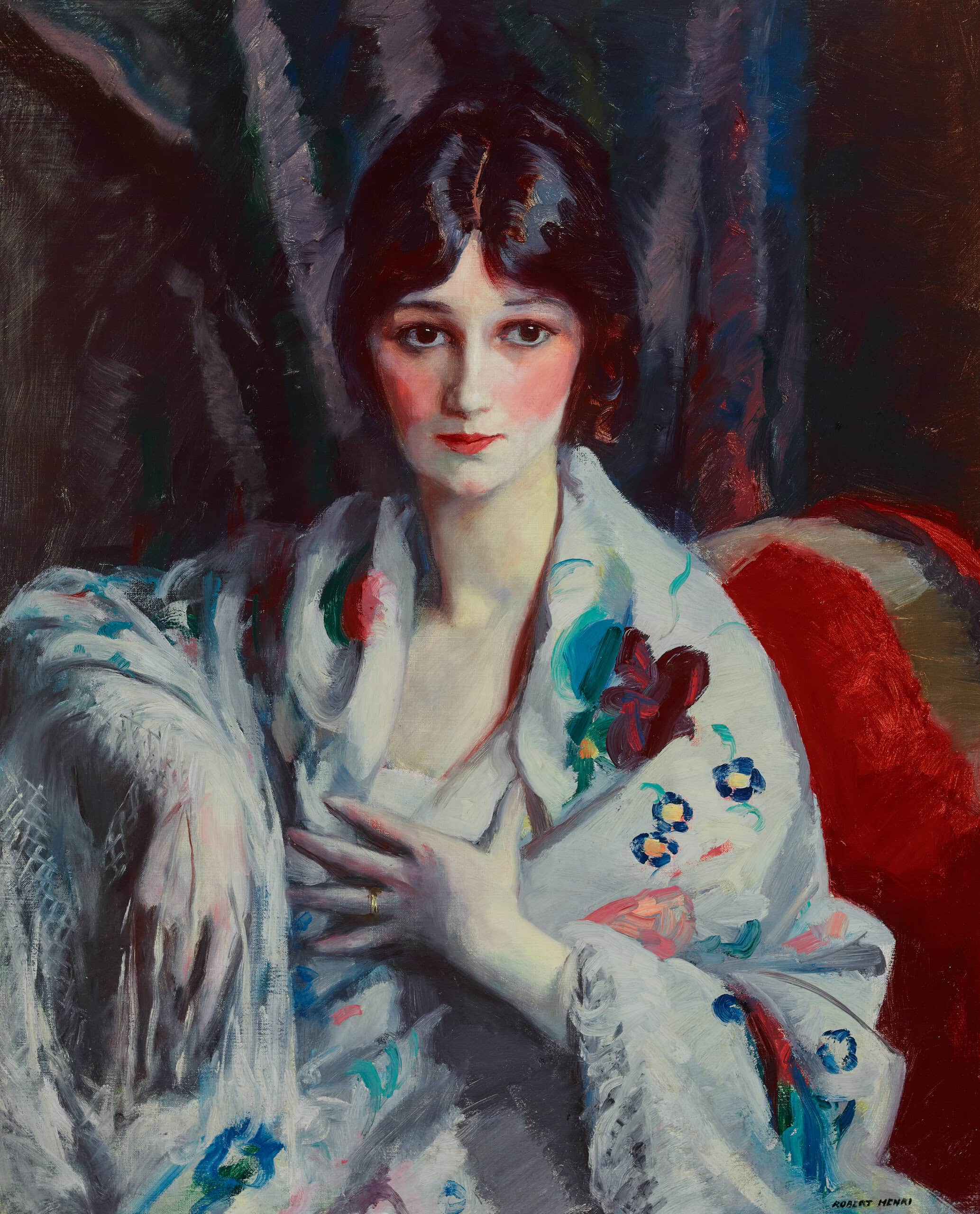 portrait of a woman with black hair sitting and wearing a white shall with flowers on it